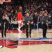 Three arena employees mop the basketball court during an NBA game.