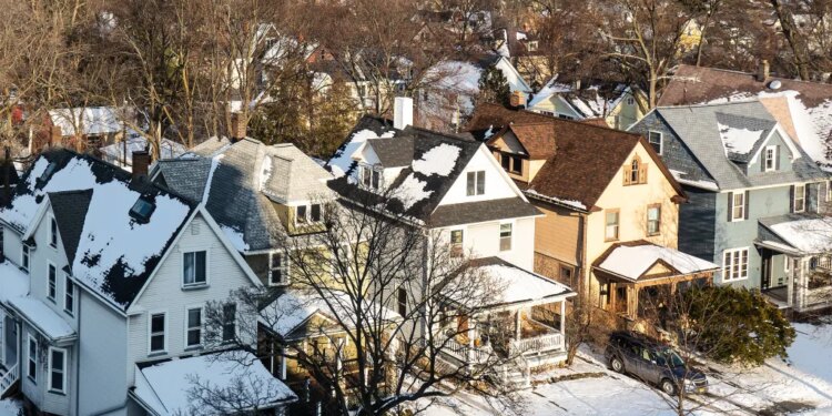 Aerial view of a snowy Rochester suburb with houses and bare trees.