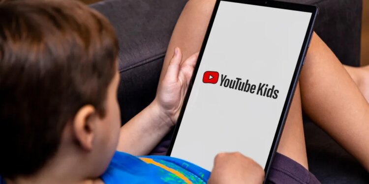 A child views the YouTube Kids logo on a tablet screen.