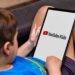 A child views the YouTube Kids logo on a tablet screen.