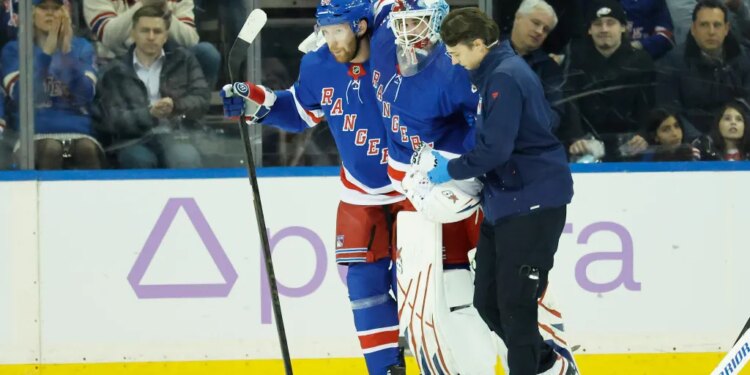 New York Rangers goaltender Igor Shesterkin is helped off the ice by a trainer and New York Rangers defenseman Vladislav Gavrikov.