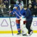 New York Rangers goaltender Igor Shesterkin is helped off the ice by a trainer and New York Rangers defenseman Vladislav Gavrikov.