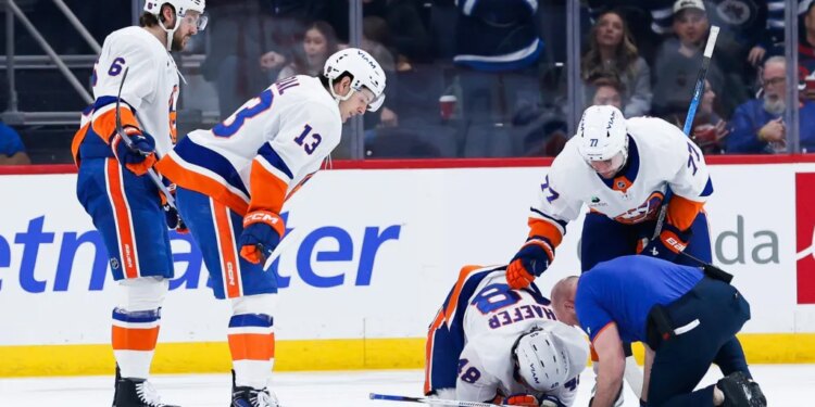 Matthew Schaefer is tended to by a trainer and some teammates  after a Winnipeg goal during the first period of the Islanders' 5-4 road loss to the Jets on Jan. 13, 2025.
