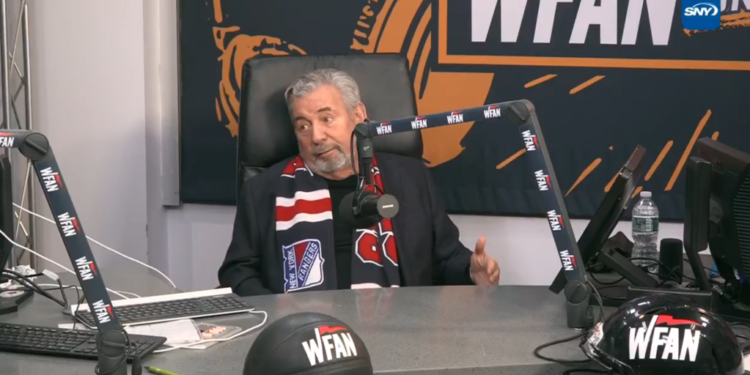 A man wearing a New York Rangers scarf sits at a desk with a WFAN microphone, a basketball, and a football helmet, all branded with WFAN.