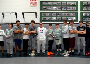 Coach Brian DeGaetano with the JFK High School wrestling team, including seven sets of siblings and a pair of cousins.