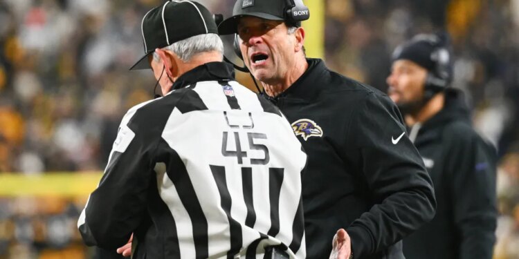 Baltimore Ravens head coach John Harbaugh talks with an official.
