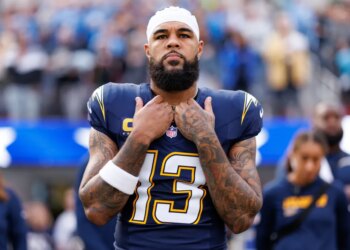 Keenan Allen, a wide receiver for the Los Angeles Chargers, wearing a white bandana, number 13 jersey, with tattoos on both arms, stands with his hands clasped at his chest.