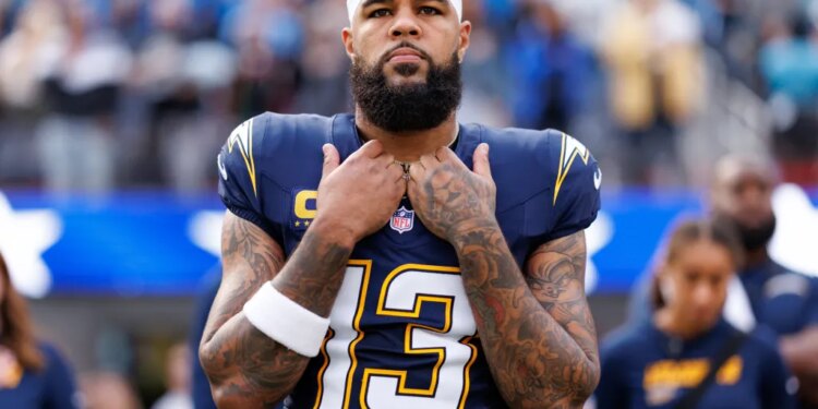 Keenan Allen, a wide receiver for the Los Angeles Chargers, wearing a white bandana, number 13 jersey, with tattoos on both arms, stands with his hands clasped at his chest.