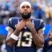 Keenan Allen, a wide receiver for the Los Angeles Chargers, wearing a white bandana, number 13 jersey, with tattoos on both arms, stands with his hands clasped at his chest.
