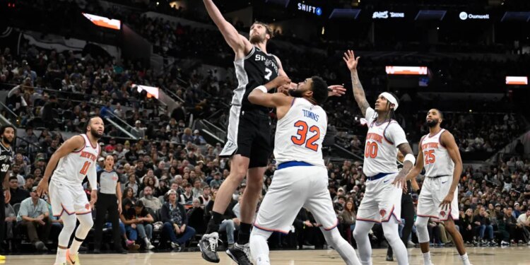 San Antonio Spurs center Luke Kornet (7) grabs the rebound against New York Knicks center Karl-Anthony Towns (32) during the second half of an NBA basketball game, Wednesday, Dec. 31, 2025, in San Antonio.