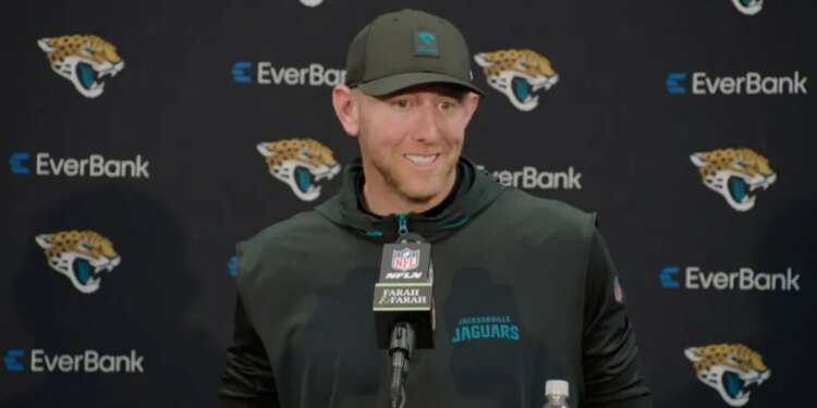 Jaguars head coach Liam Coen smiling while speaking into a microphone.