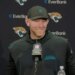 Jaguars head coach Liam Coen smiling while speaking into a microphone.