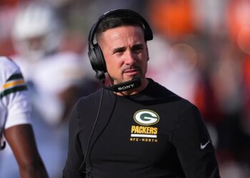 Green Bay Packers head coach Matt LaFleur wearing a headset and a black long-sleeved shirt with the Packers logo.