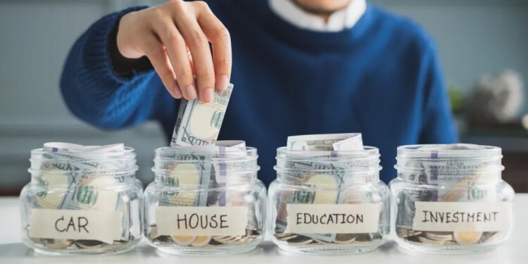 Man putting money into a jar labeled "House," among jars labeled "Car," "Education," and "Investment."
