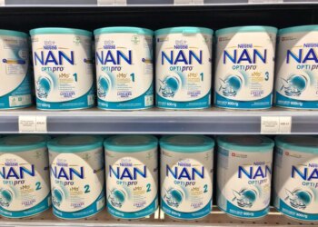 A supermarket shelf stocked with multiple cans of Nestle NAN OPTIPRO baby milk formula.