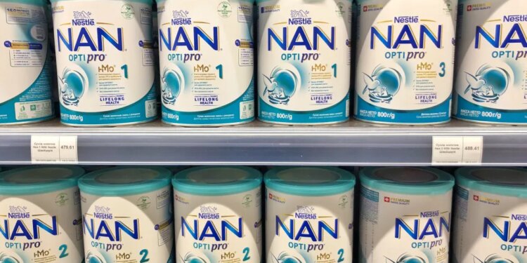 A supermarket shelf stocked with multiple cans of Nestle NAN OPTIPRO baby milk formula.