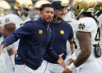 Notre Dame head coach Marcus Freeman greets players on the sideline.