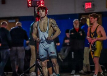 Anthony Knox Jr., a three-time state wrestling champion, stands in his wrestling singlet, facing a competitor.