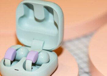 Sony LinkBuds Clip in their open case on a peach surface.