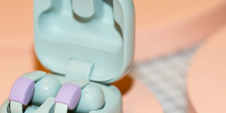 Sony LinkBuds Clip in their open case on a peach surface.