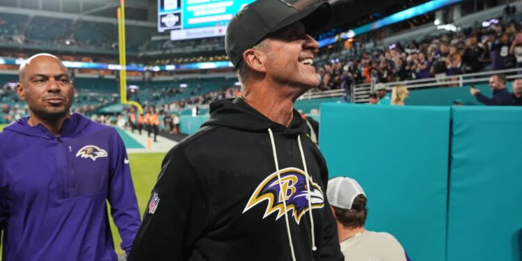 Baltimore Ravens head coach John Harbaugh smiles while walking off the field.