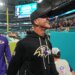 Baltimore Ravens head coach John Harbaugh smiles while walking off the field.