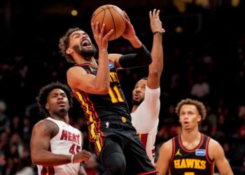 Atlanta Hawks guard Trae Young (11) shoots past Miami Heat guard Davion Mitchell (45) during the first half of an NBA basketball game, Friday, Dec. 26, 2025, in Atlanta.