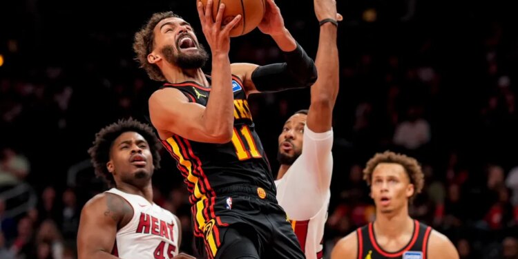 Atlanta Hawks guard Trae Young (11) shoots past Miami Heat guard Davion Mitchell (45) during the first half of an NBA basketball game, Friday, Dec. 26, 2025, in Atlanta.
