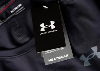 A close-up of a black Under Armour tag with "HeatGear" written below it, hanging from a black compression shirt.