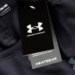 A close-up of a black Under Armour tag with "HeatGear" written below it, hanging from a black compression shirt.