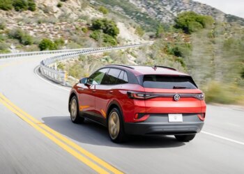 Red Volkswagen ID.4 electric vehicle driving on a winding road.