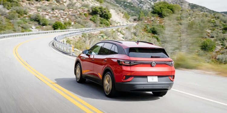 Red Volkswagen ID.4 electric vehicle driving on a winding road.