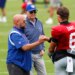 Giants head coach Brian Daboll fist-bumps quarterback Jaxson Dart, with owner John Mara standing behind them, on a football field.