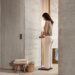 Woman in modern bathroom stands on Body Scan 2 scale while holding onto the handles