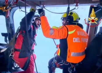 Two Italian fire brigade rescue workers inside a helicopter.