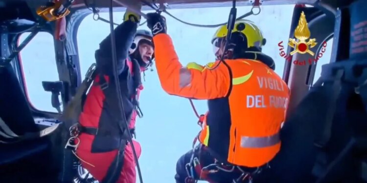 Two Italian fire brigade rescue workers inside a helicopter.