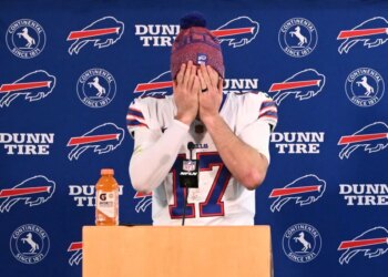 Buffalo Bills quarterback Josh Allen covers his face with his hands at a news conference.