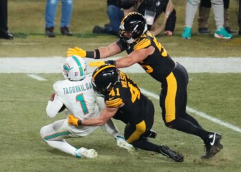 Tua Tagovailoa is sacked by Payton Wilson and Alex Highsmith during an NFL football game.