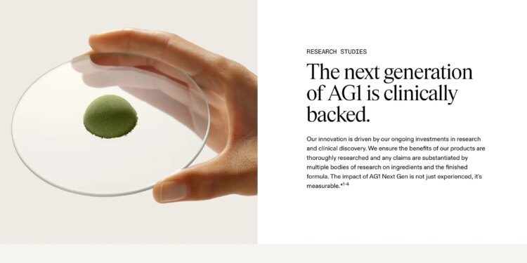Screenshot of AG1’s research page that says “The next generation of AG1 is clinically backed” with a picture of someone’s hand holding a disc resembling a petri dish with a mound of green powder in the center.