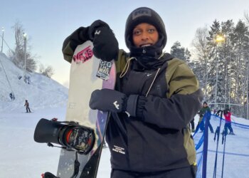 Maryan Hashi holding her snowboard at a ski resort.