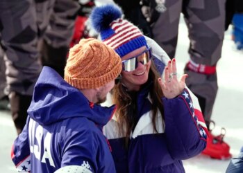 Breezy Johnson looks at the engagement ring she was given by Connor Watkins, at the finish area of an alpine ski, women's super-G race, at the 2026 Winter Olympics, in Cortina d'Ampezzo, Italy, Thursday, Feb. 12, 2026.