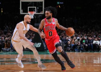 Chicago Bulls player Coby White dribbles the ball past a Boston Celtics defender.