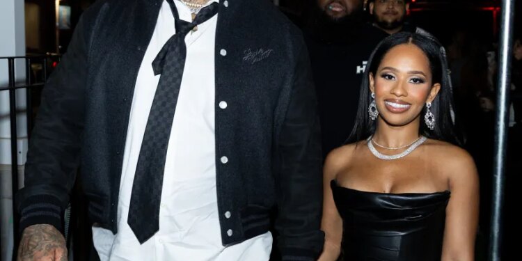 Trent Williams and a woman hold hands, smiling while walking at night.