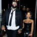 Trent Williams and a woman hold hands, smiling while walking at night.