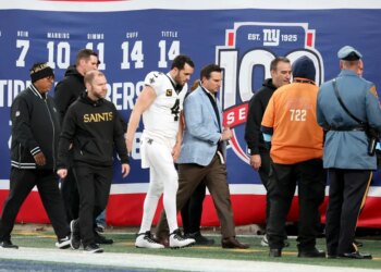 Saints football players walking on the field with team staff.