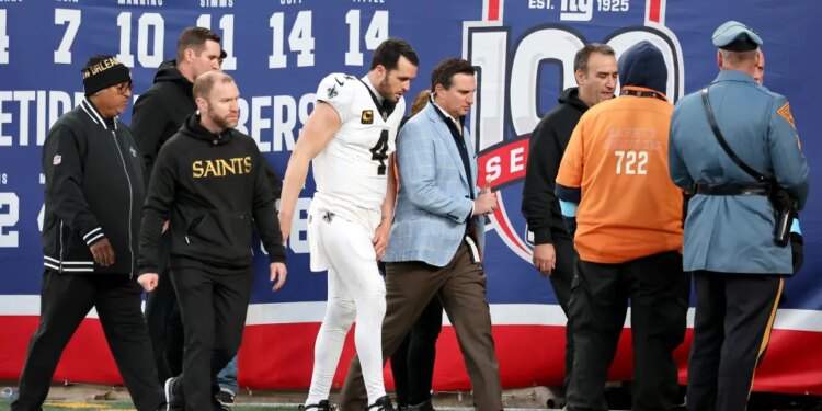 Saints football players walking on the field with team staff.