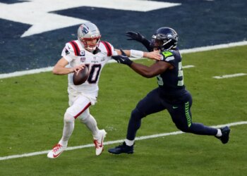 Drake Maye #10 of the New England Patriots is forced out of the pocket during the second quarter.
