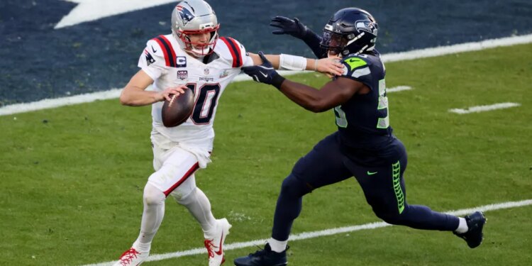 Drake Maye #10 of the New England Patriots is forced out of the pocket during the second quarter.
