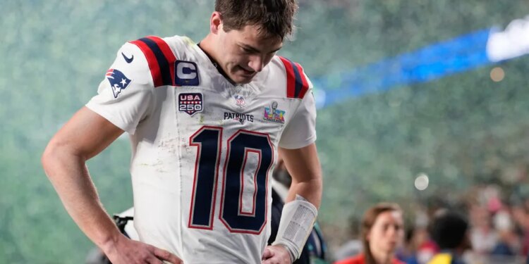 New England Patriots quarterback Drake Maye walks off the field after a Super Bowl 60 loss, looking dejected.