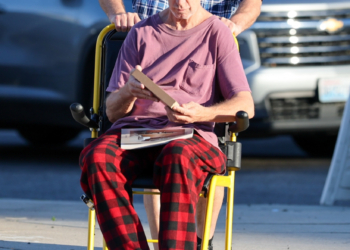 Andy Dick in a wheelchair, being pushed by a companion, on an afternoon outing in Los Angeles.